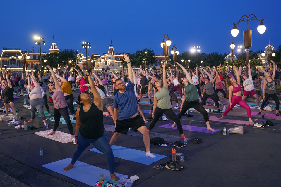 Nearly 2,000 Cast Members practice sunrise yoga celebrating International Yoga Day in front of Cinderella Castle at the Magic Kingdom Park at Walt Disney World Tuesday, June 21, 2022, in Lake Buena Vista, Fla. (AP Photo/John Raoux)