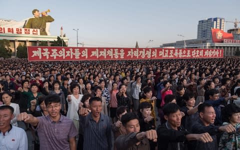 Participants of a mass rally shout slogans as they gather before a banner reading 'let us beat down the sanctions of the imperialists with great progress of self-reliance' on Kim Il-Sung sqaure in Pyongyang on September 23, 2017 - Credit: AFP