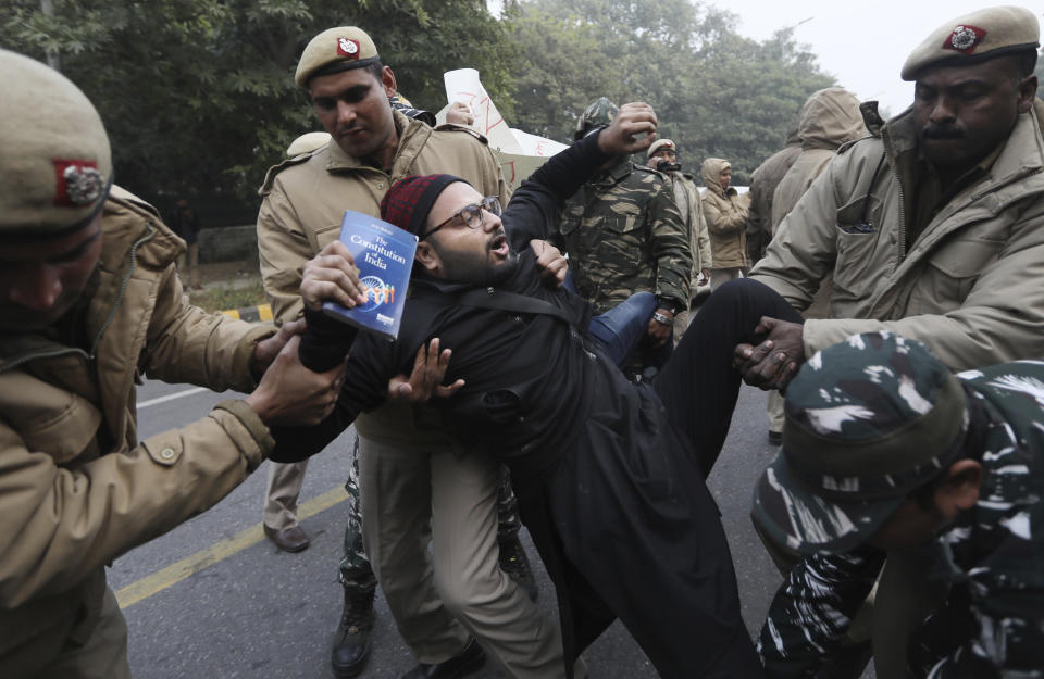 Police officers detain a protesting student, holding a book on the Indian constitution, outside Uttar Pradesh Bhawan during a protest against a new citizenship law and violence by police in the state, in New Delhi, India, Friday, Dec. 27, 2019. The new citizenship law allows Hindus, Christians and other religious minorities who are in India illegally to become citizens if they can show they were persecuted because of their religion in Muslim-majority Bangladesh, Pakistan and Afghanistan. It does not apply to Muslims. (AP Photo/Manish Swarup)