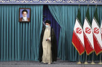 In this picture released by the official website of the office of the Iranian supreme leader, Supreme Leader Ayatollah Ali Khamenei arrives to vote at a polling station at Imam Khomeini mosque in his residence compoand, in Tehran, Iran, Friday, June 18, 2021. Iran began voting Friday in a presidential election tipped in the favor of a hard-line protege of Supreme Leader Ayatollah Ali Khamenei, fueling public apathy and sparking calls for a boycott in the Islamic Republic. A portrait of the late revolutionary founder Ayatollah Khomeini hangs at left. (Office of the Iranian Supreme Leader via AP)