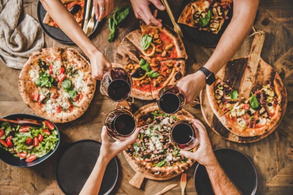 Family celebrate Italian dinner by clinking wine glasses