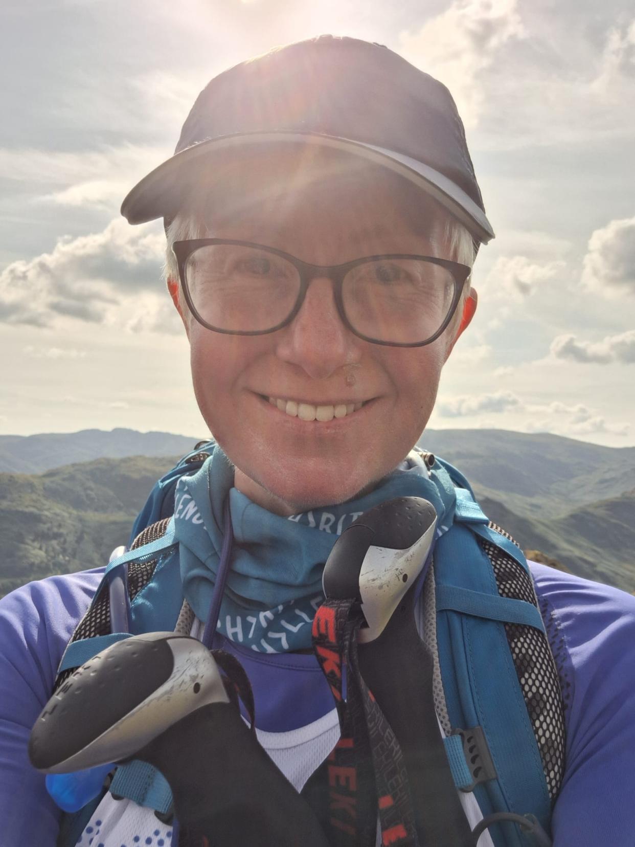 Jackie Scully smiling at the camera on top of a peak in the Lake District 