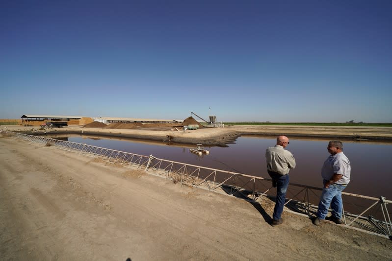 Dairy farmer Joey Airoso talks with SoCalGas project manager Ty Korenwinder as they look over one of the farm's holding ponds in Pixley