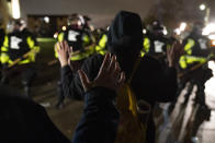 Demonstrators raise their hands while facing off against a perimeter of police as they defy an order to disperse during a protest against the police shooting of Daunte Wright, late Monday, April 12, 2021, in Brooklyn Center, Minn. (AP Photo/John Minchillo)