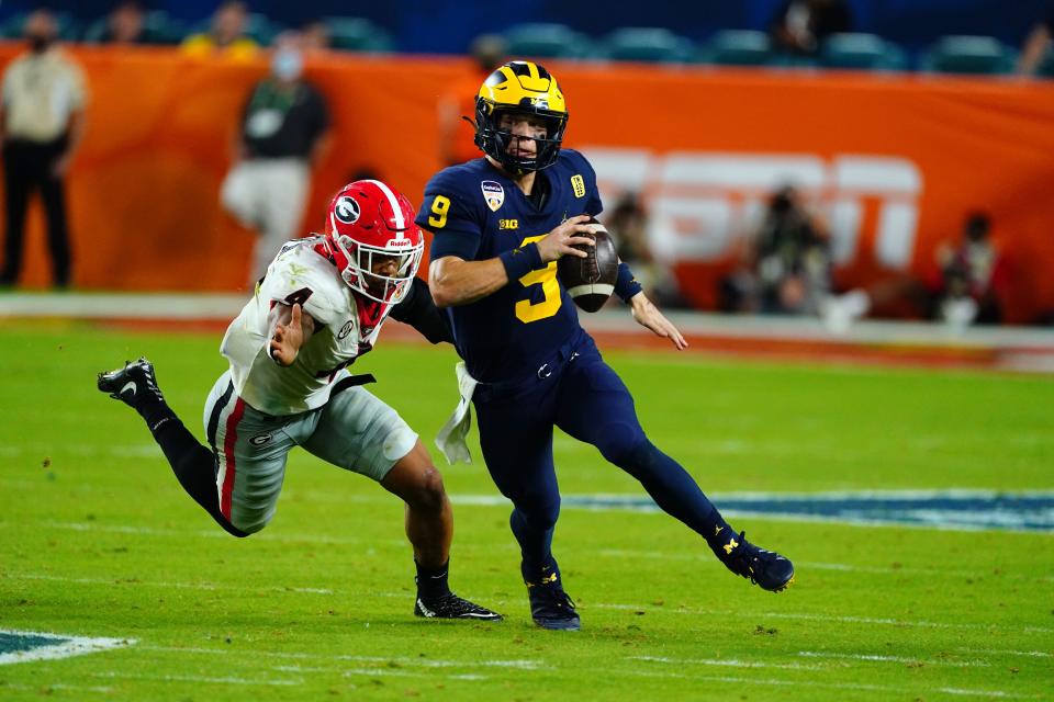 Michigan quarterback J.J. McCarthy (9) runs away from Georgia linebacker Nolan Smith (4) during the fourth quarter in the 2021 Orange Bowl at Hard Rock Stadium.