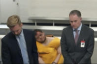 FILE - In this image from El Paso County District Court video, Anderson Lee Aldrich, center, can be seen slumped over in a chair in a brief video appearance from jail in Colorado Springs, Colo., Wednesday, Nov. 23, 2022. A year and a half before the Colorado Springs gay nightclub shooting that left five dead, Aldrich, the alleged shooter, was accused of threatening to kill his grandparents if they stood in the way of his plans to become “the next mass killer.” (El Paso County District Court via AP, File)