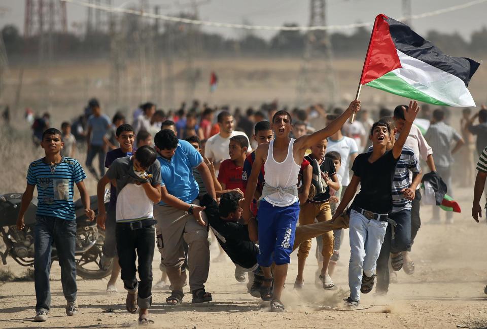 Palestinians carry a wounded protester after Israeli troops fired tear gas canisters during clashes after a protest in solidarity with Al-Aqsa mosque near the border with Israel, east of Gaza Strip September 27, 2013. (REUTERS/Mohammed Salem)