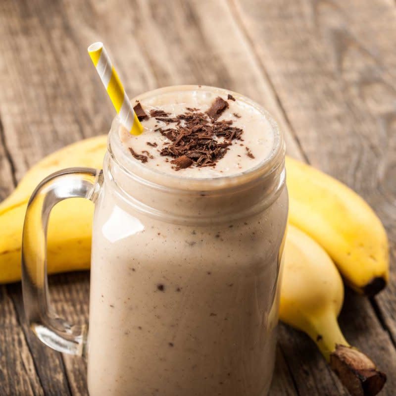 Banana chocolate smoothie and banana on wooden table