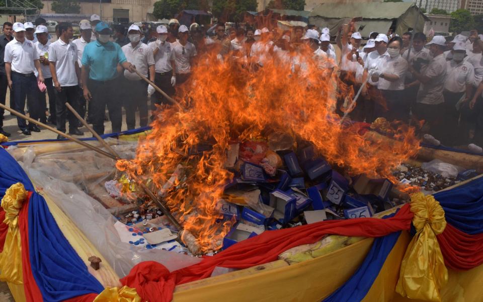 Cambodian officials torch a pile of drugs during a destruction ceremony to mark the UN's "International Day against Drug Abuse and Illicit Trafficking" in Phnom Penh - Credit: TANG CHHIN SOTHY/AFP