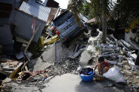 <p> A boy sits with items salvaged from the ruins of a family member's house in the Balaroa neighborhood in Palu, Central Sulawesi, Indonesia Indonesia, Tuesday, Oct. 2, 2018. Desperation was visible everywhere Tuesday among victims receiving little aid in areas heavily damaged by a massive earthquake and tsunami, four days after the disaster devastated parts of Indonesia's central Sulawesi island. (AP Photo/Dita Alangkara) </p>