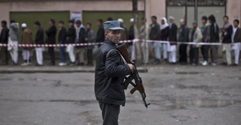 An Afghan policeman stands guard while voters line up to enter a polling station and cast their ballots in Kabul, Afghanistan, Saturday, April 5, 2014. Across Afghanistan, voters turned out in droves Saturday to cast ballots in a crucial presidential election. The Taliban threatened to target voters and polling places, but there were few instances of violence. Instead, those wanting to cast ballots joined long lines and expressed pride for security forces guarding the election and a willingness to stand up for their country. (AP Photo/Muhammed Muheisen)