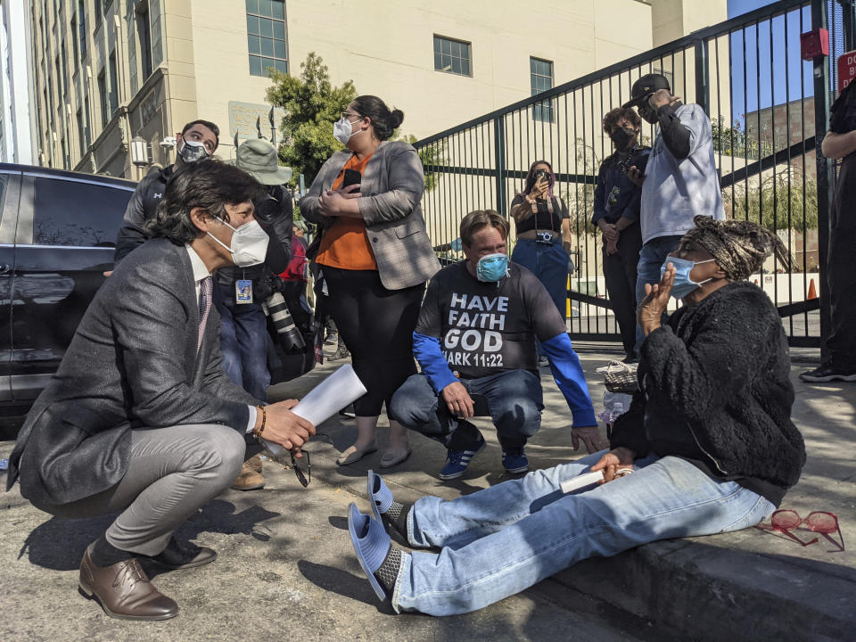 Los Angeles City Council Member Kevin de Leon, left, talks to Michelle Coultier, 51, a homeless person since 2013, outside the Downtown Women's Center in Los Angeles Thursday, Feb. 4, 2021. Helping HandsUps Pastor Donald Dermit, sits in the middle. U.S. District Judge David Carter, not seen, presided from a folding table Thursday under a large tent in the shelter's parking lot, where encampments line the surrounding sidewalks. The judge is overseeing a case that accuses the city and county of failing to address the desperate situations that homeless people face. Carter said he held the hearing because he worries people are "not seeing and feeling" the reality on the ground. (AP Photo/Damian Dovarganes)