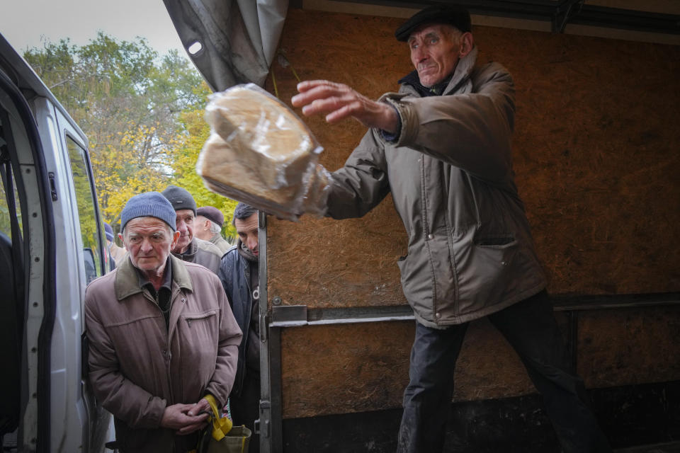 A volunteer unloads bread as local residents wait for free bread distribution in Bakhmut, the site of the heaviest battle against the Russian troops in the Donetsk region, Ukraine, Friday, Oct. 28, 2022. (AP Photo/Efrem Lukatsky)