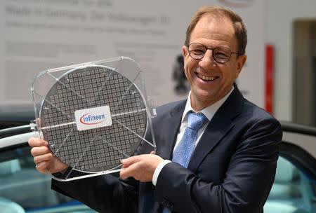 Reinhard Ploss, CEO of German semiconductor manufacturer Infineon, holds a wafer while posing for pictures at the company's annual shareholder meeting in Munich, Germany February 21, 2019. REUTERS/Andreas Gebert