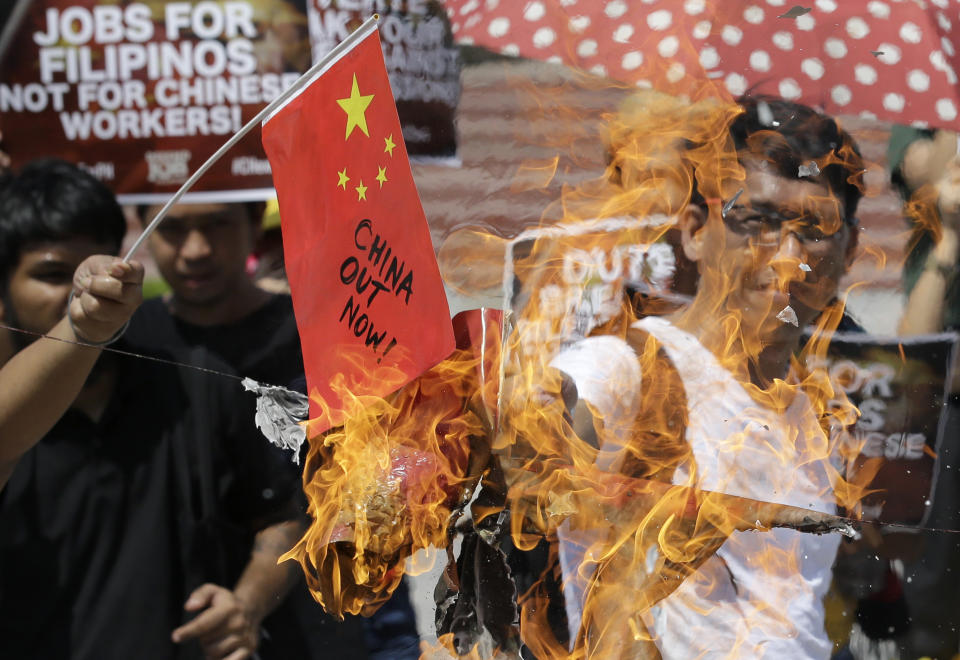 FILE - In this June 18, 2019, file photo, a protester burns mock Chinese flags at Manila's Rizal Park, Philippines, to condemn a recent incident that involved a Chinese fishing vessel hitting a Filipino fishing boat. The Philippines' top diplomat says he has filed a diplomatic protest after an anchored fishing boat was hit by a suspected Chinese vessel which then abandoned the 22 Filipino fishermen as the boat sank in the disputed South China Sea. (AP Photo/Aaron Favila, File)