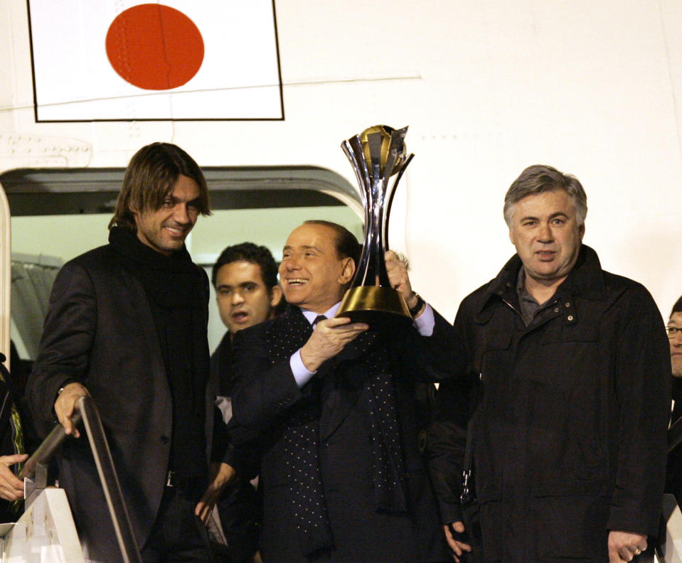 FILE - AC Milan's President Silvio Berlusconi, center, flanked by team coach Carlo Ancelotti, right, and by team captain Paolo Maldini, holds the FIFA Club World Cup soccer championship trophy, upon their arrival at Milan's Malpensa airport, Italy, Dec. 17, 2007. Berlusconi, the boastful billionaire media mogul who was Italy's longest-serving premier despite scandals over his sex-fueled parties and allegations of corruption, died, according to Italian media. He was 86. (AP Photo/Antonio Calanni, File)