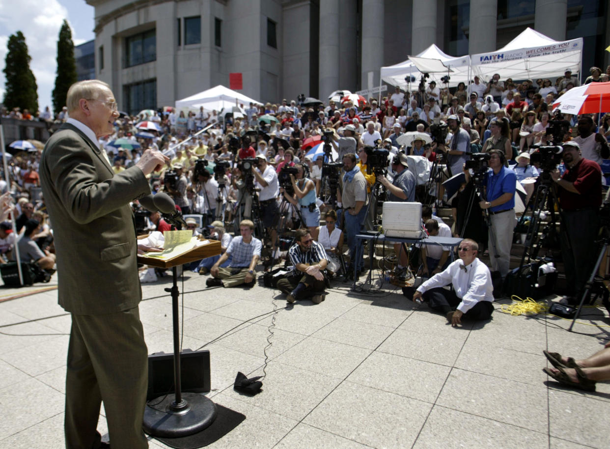 Evangelical leader James Dobson stands at a podium outside in front of a crowd.