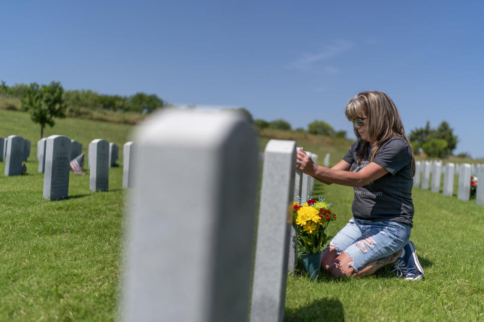 Barbie Rohde touches the tombstone of her son, Army Sgt. Cody Bowman, at the Dallas-Fort Worth National Cemetery, Sunday, June 11, 2023, in Dallas. For decades, discussions of suicide prevention skirted fraught questions about firearms; the Army has punted implementing measures that might be controversial. But a growing consensus movement has taken hold, among researchers, the Veterans Administration, ordinary people like Rohde: if this country wants to get serious about addressing an epidemic of suicide, it must find a way to honor veterans and active-duty service members, respect their rights to own a gun, but keep it out of their hands on their darkest days. (AP Photo/David Goldman)