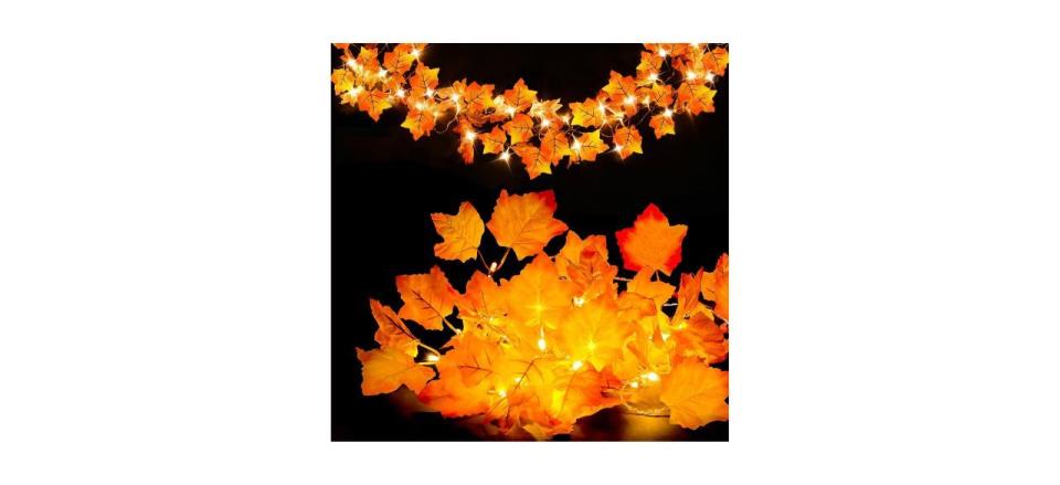 A lighted garland of fake orange maple leaves on a black background