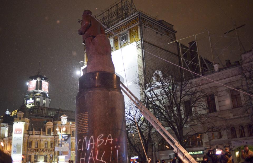 A hawser is attached to a statue of Soviet state founder Vladimir Lenin as protesters topple the statue during a rally organized by supporters of EU integration in Kiev