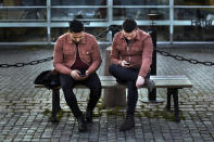 FILE - In this Wednesday, April 8, 2020 file photo two men check their phones as they sit near the harbor in Stockholm, Sweden. (AP Photo/Andres Kudacki, File)