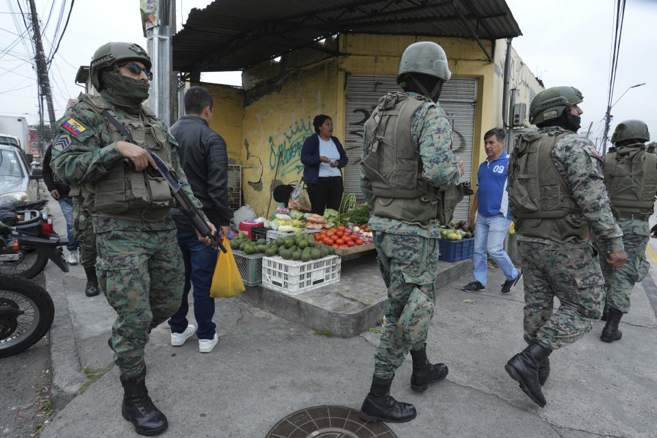 Soldados patrullan el perímetro de la prisión de Inca durante un estado de emergencia mientras un vendedor de alimentos trabaja en la acera en Quito, Ecuador, el martes 9 de enero de 2024, tras la aparente fuga de un poderoso líder de una pandilla de la cárcel. El presidente Daniel Noboa decretó el lunes estado de emergencia nacional, una medida que permite a las autoridades suspender los derechos de las personas y movilizar a los militares en lugares como las cárceles. El gobierno también impuso un toque de queda desde las 23:00 horas hasta las 5:00 AM. (Foto AP/Dolores Ochoa)