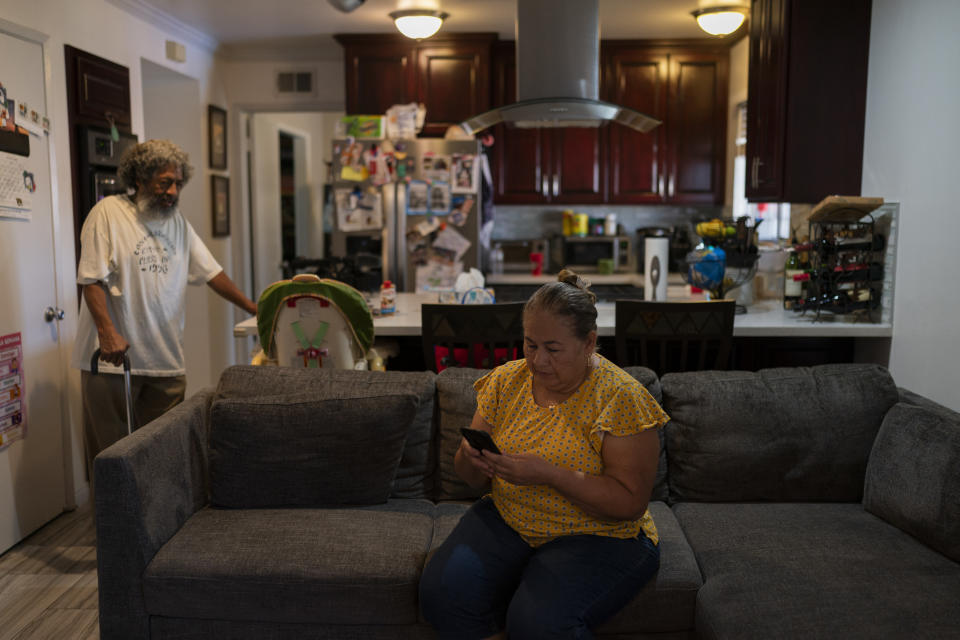 Ana Sandoval, mother of Eyvin Hernandez, a Los Angeles attorney who has been detained for five months in Venezuela, checks her phone while talking with Hernandez's step-father, Pedro Martinez, in Compton, Calif., Monday, Aug. 29, 2022. The Los Angeles attorney detained for five months in Venezuela is pleading for help from the Biden administration, saying in a secretly recorded jailhouse message that he feels forgotten by the U.S. government as he faces criminal charges at the hands of one of the nation's top adversaries. (AP Photo/Jae C. Hong)