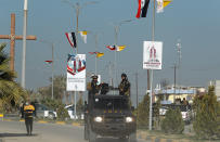 FILE - Iraqi security forces pass by Iraq and the Vatican flags and posters announcing visit of the Pope Francis in a street in Qaraqosh, Iraq, Monday, Feb. 22, 2021. Iraq was estimated to have more than 1 million Christians before the 2003 U.S.-led invasion that toppled dictator Saddam Hussein. Now, church officials estimate only few hundred remain within Iraq borders. The rest are scattered across the globe, resettling in far-flung places like Australia, Canada and Sweden as well as neighboring countries. (AP Photo/Hadi Mizban, File)