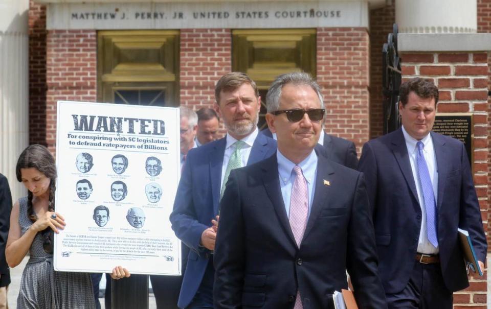 After a hearing involving a top Westinghouse executive in the ongoing SCANA debacle, acting Acting United States Attorney Rhett DeHart and members of his staff walk past activist Leslie Minerd at the Matthew J. Perry federal courthouse.