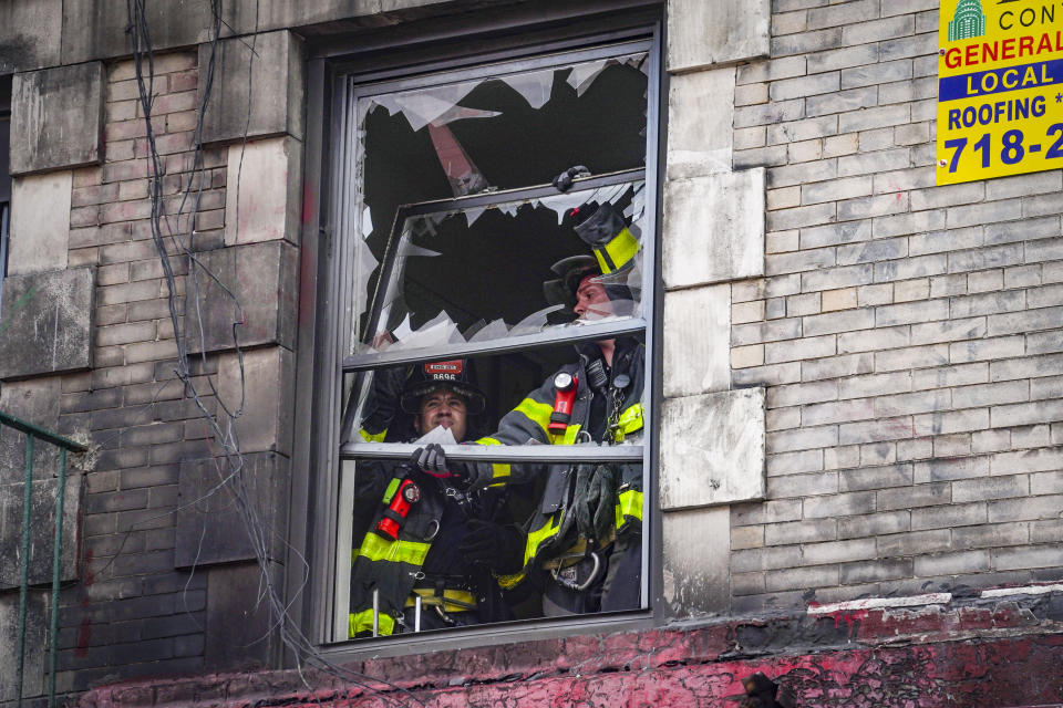 Firefighters remove windows from a six-story building in the aftermath of a fire which authorities say started at an e-bike shop and spread to upper-floor apartments, Tuesday June 20, 2023, in New York. (AP Photo/Bebeto Matthews)