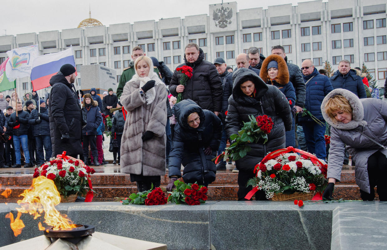 People lay flowers near the Eternal Flame memorial.