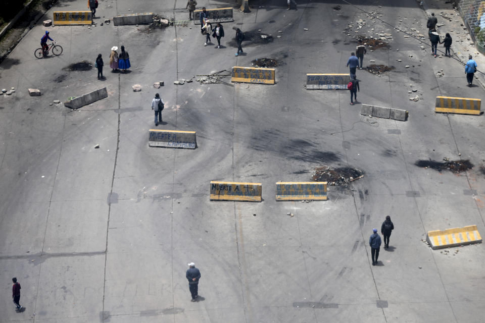 Pedestrians walk on a highway strewn with traffic barriers used by supporters of former President Evo Morales to block a highway in El Alto, Bolivia, Saturday, Nov. 16, 2019. Morales stepped down following nationwide protests over suspected vote-rigging in an Oct. 20 election in which he claimed to have won a fourth term in office. An Organization of American States audit of the vote found widespread irregularities. Morales has denied there was fraud. (AP Photo/Natacha Pisarenko)