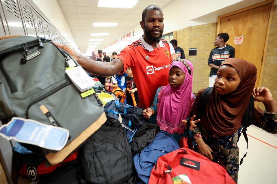 Abdullahi Osman holds up a backpack while helping Hawa Musa and Ifrah Hassan pick out backpacks during Refugee Back to School Night at Granite Park Junior High in South Salt Lake on Monday, Aug. 7, 2023. | Kristin Murphy, Deseret News