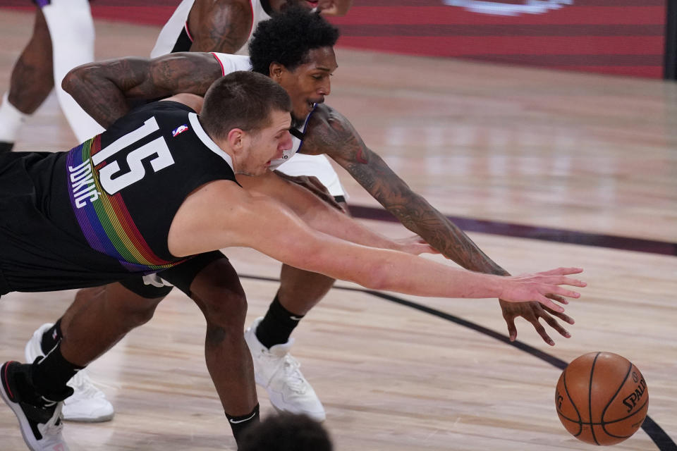 Denver Nuggets' Nikola Jokic (15) reaches for the ball with Los Angeles Clippers' Lou Williams, top, during the first half of an NBA conference semifinal playoff basketball game Monday, Sept. 7, 2020, in Lake Buena Vista, Fla. (AP Photo/Mark J. Terrill)