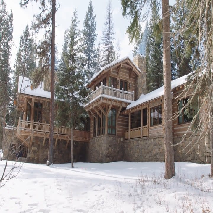 The front of the house has snow on it and the ground is covered with snow