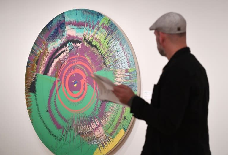 A man looks at a Damien Hirst with David Bowie painting titled, "Beautiful, hallo, space-boy" at Sotheby's on September 26, 2016