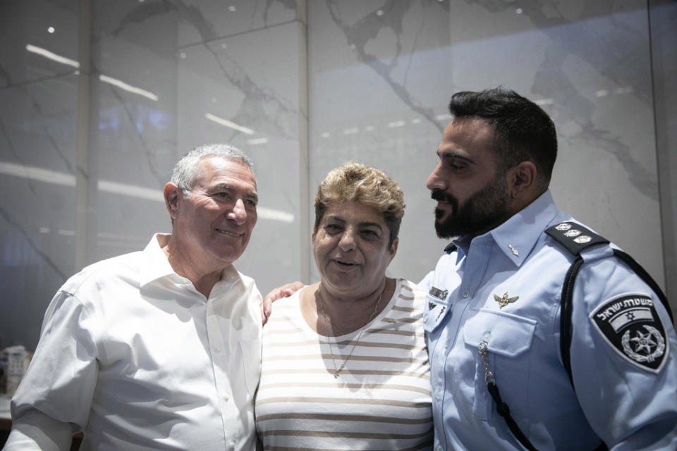 Rachel Edri, center, from Ofakim in southern Israel, poses for a portrait with Doron Almog, Jewish Agency Chairman, left, during a meeting with U.S. President Joe Biden, in Tel Aviv, Israel, Wednesday, Oct. 18, 2023. Edri, a 65 year old from the southern town of Ofakim, has become an unlikely folk hero among Israelis for narrowly escaping death at the hands of Hamas militants by feeding them tea and cookies. Edri and her husband spent nearly 20 hours in her house, entertaining five armed militants, before a rescue squad of local police were able to come to her rescue. (Miriam Alster/Pool Photo via AP)