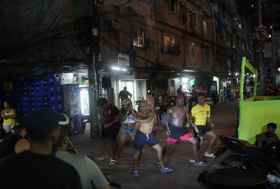 ARCHIVO - Jóvenes iluminados por el faro de una motocicleta interpretan el estilo de baile callejero passinho en la favela de Rocinha de Río de Janeiro, Brasil el 11 de abril de 2024. El passinho, o "pequeño paso", creado en la década del 2000 por jóvenes de las favelas de Río, fue declarado "patrimonio cultural inmaterial" por los legisladores estatales. (Foto AP/Silvia Izquierdo, archivo)