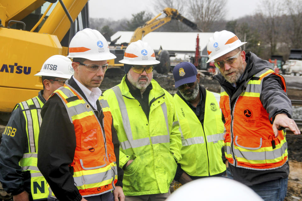 Transportation Secretary Pete Buttigieg, left, Randy Keltz, manager of tank car safety programs with the Federal Railroad Administration (FRA), second from left, and Karl Alexy, chief safety officer with FRA, far right, look at a burned Norfolk Southern railcar that had been carrying hazardous materials, Thursday, Feb. 23, 2023, in East Palestine, Ohio, at the site of a Norfolk Southern train derailment. (Allie Vugrincic/The Vindicator via AP, Pool)