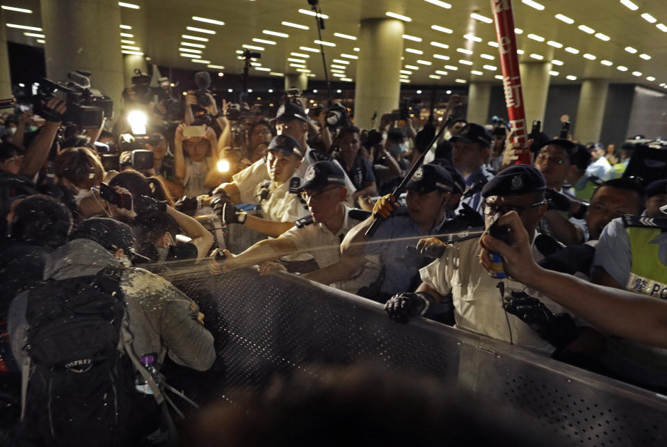 Police officers use pepper spray against protesters in a rally against the proposed amendments to the extradition law at the Legislative Council in Hong Kong during the early hours of Monday, June 10, 2019. The extradition law has aroused concerns that this legislation would undermine the city's independent judicial system as it allows Hong Kong to hand over fugitives to the jurisdictions that the city doesn't currently have an extradition agreement with, including mainland China, where a fair trial might not be guaranteed. (AP Photo/Vincent Yu)