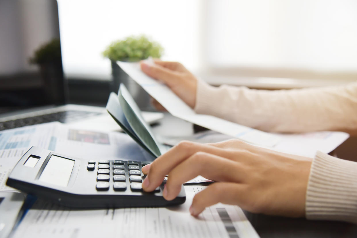 Close up of woman hand calculating her monthly expenses with calculator.  Debt.