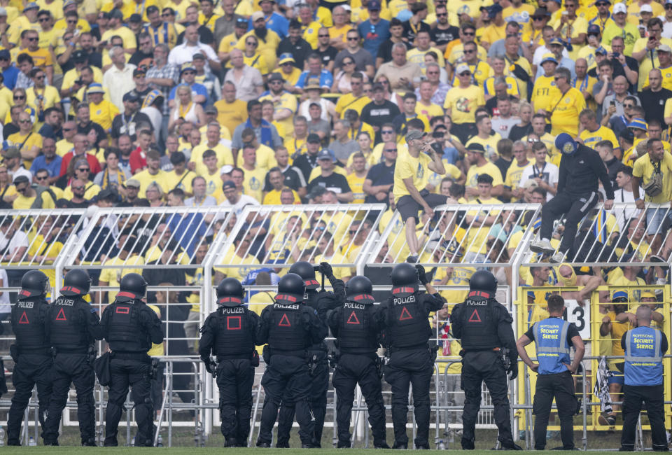 A police cordon stands in front of a block of Lok fans during the German Soccer Cup game between Eintracht Frankfurt and Lokomotive Leipzig at Bruno Plache Stadium in Leipzig, Germany, Sunday Aug. 13, 2023. (Hendrik Schmidt/dpa via AP)