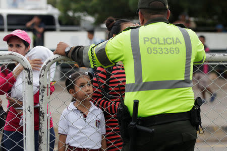 A Colombian policeman stand in front of people who are trying to cross into Venezuela from Colombia via the Simon Bolivar international bridge in Cucuta, Colombia August 8, 2018. REUTERS/Luisa Gonzalez