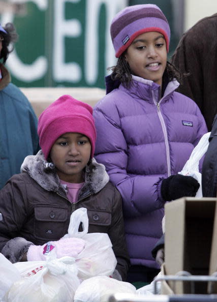 Sasha Obama (L) and Malia Obama, daughters of President-elect Barack Obama, pass out food at St. Columbanus Parrish and School November 26, 2008, in Chicago, Illinois. Obama earlier intruduced Paul Volckeras the chair of his Economic Recovery Advisory Board. (Photo by Frank Polich-Pool/Getty Images)