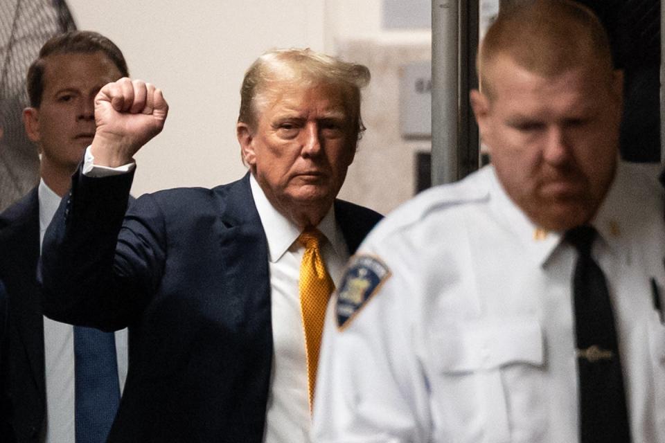 A man in a navy blue jacket and gold tie raising his fist.