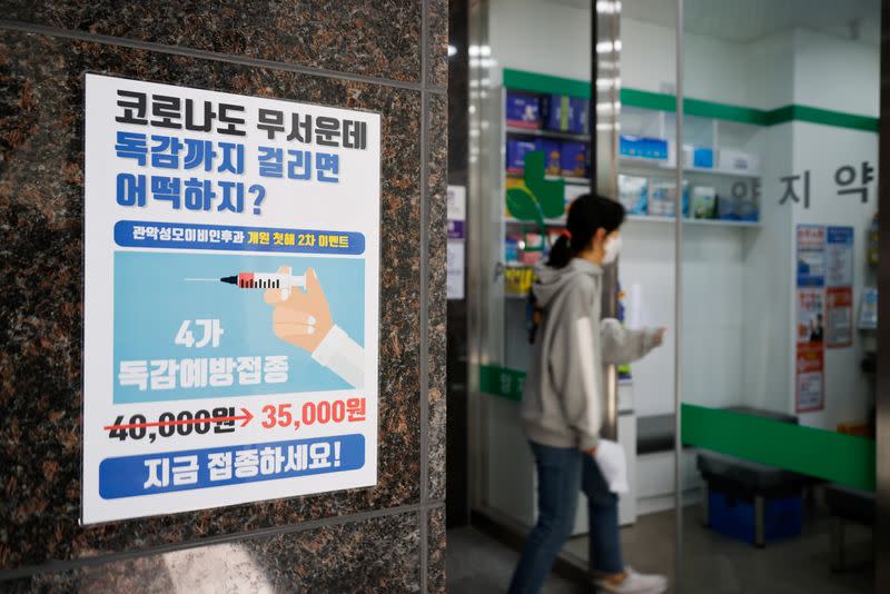 A woman walks past a poster encouraging people to get an influenza vaccine in Seoul