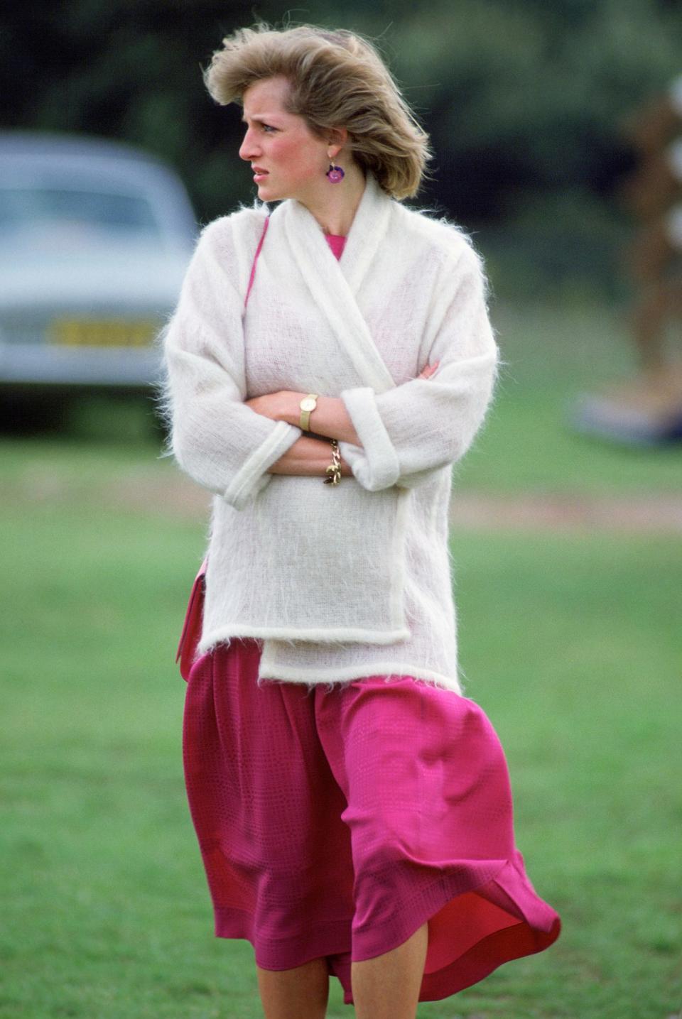 <p>The royal wrapped up in a white cardigan sans buttons over a pink dress for a 1984 polo match.</p>