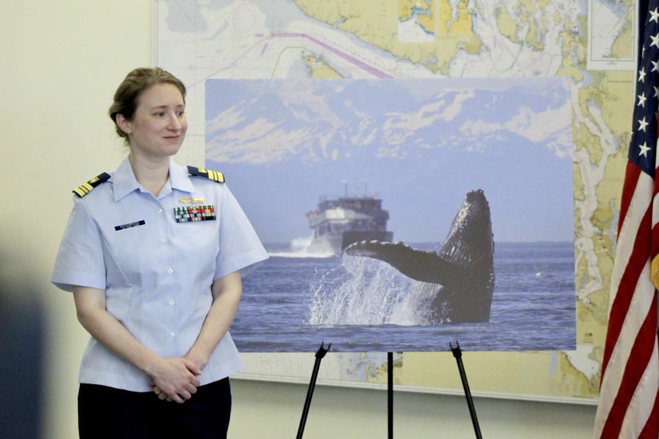 U.S. Coast Guard Lt. Cmdr. Margaret Woodbridge stands next to a picture of a humpback whale during a press conference in Seattle, Wednesday, Feb. 21, 2024. The U.S. Coast Guard is launching a whale alert program, which Woodbridge is managing, in Washington's Salish Sea to help commercial and transit ships steer clear of the marine mammals. (AP Photo/Manuel Valdes)