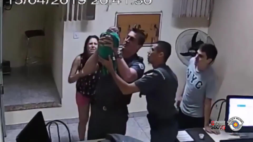 Pic Shows: The cops rescuing the choking baby in front of the crying mother;  BRAZIL: This is the moment a pair of hero cops rush to save an unconscious 21-day-old baby from choking to death using the kiss of life as the totâs terrified parents watch on.