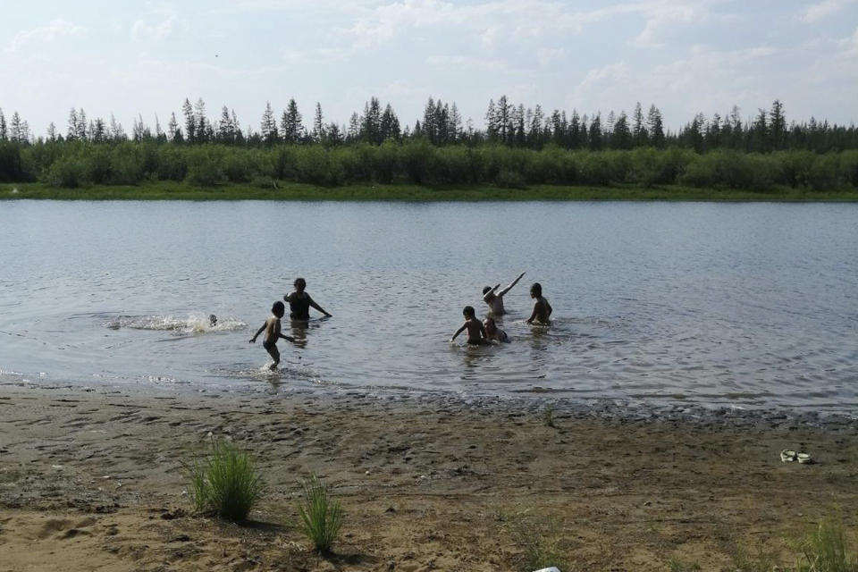 In this handout photo provided by Olga Burtseva, children play in the Krugloe lake outside Verkhoyansk, the Sakha Republic, about 4660 kilometers (2900 miles) northeast of Moscow, Russia, Sunday, June 21, 2020. A Siberian town that endures the world's widest temperature range has recorded a new high amid a hear wave that is contributing to severe forest fires. Russia's meteorological service said the thermometer hit 38 Celsius (100.4 F) on Saturday in Verkhoyansk, in the Sakha Republic about 4660 kilometers (2900 miles) northeast of Moscow. (Olga Burtseva via AP)